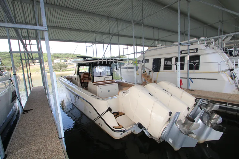 Slide: The Image of 2024 HCB 42 Lujo boat docked with powerful outboard engines in a covered marina. - 73