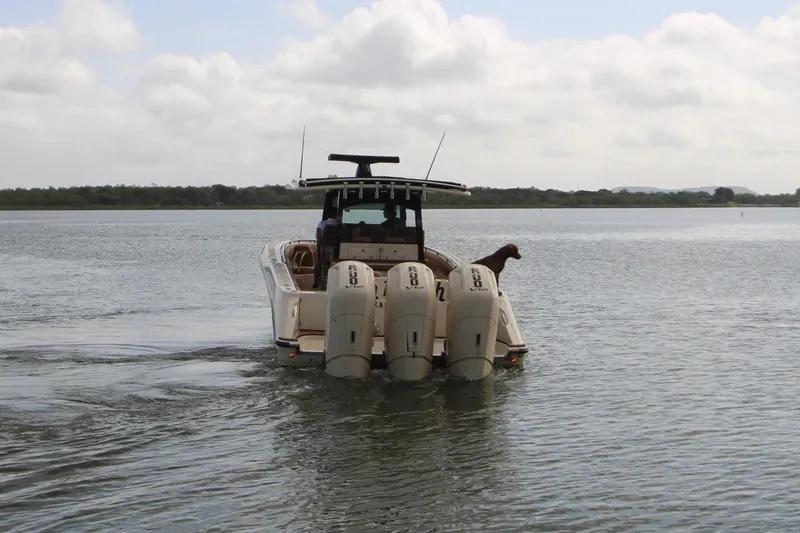 Slide: The Image of 2024 HCB 42 Lujo boat with four engines and a dog on board, cruising on calm water. - 102