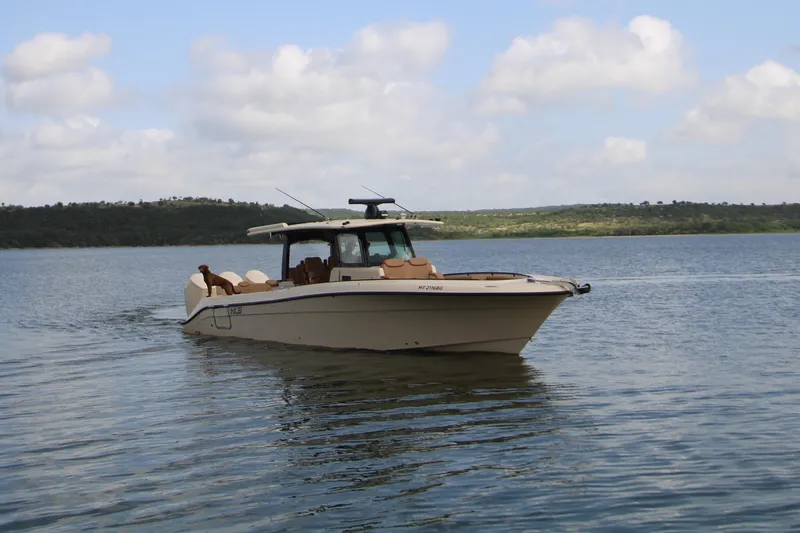 Slide: The Image of 2024 HCB 42 Lujo boat cruising on a serene lake under a partly cloudy sky. - 96