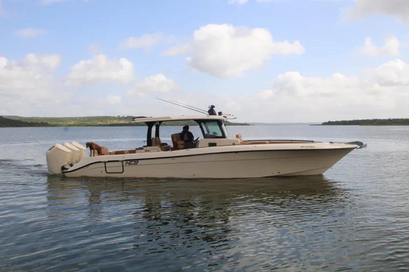 Slide: The Image of 2024 HCB 42 Lujo boat cruising on a calm lake under a partly cloudy sky. - 7