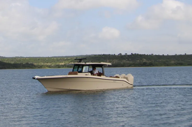 Slide: The Image of 2024 HCB 42 Lujo boat cruising on a serene lake under a partly cloudy sky. - 94