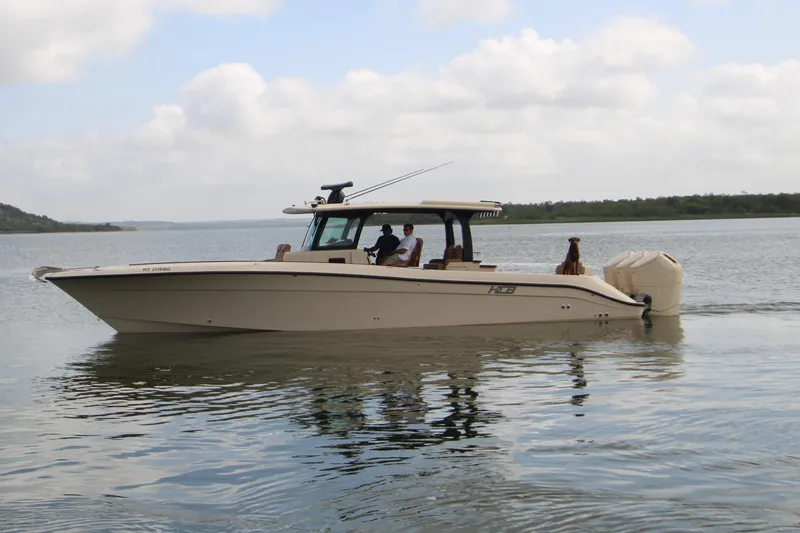 Slide: The Image of 2024 HCB 42 Lujo boat cruising on a calm lake under a cloudy sky. - 106