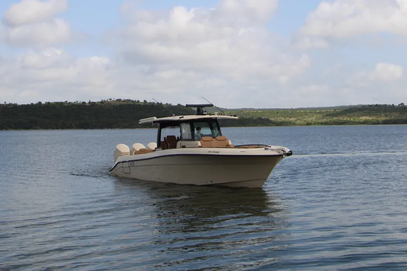 Slide: The Image of 2024 HCB 42 Lujo boat cruising on a serene lake under a partly cloudy sky. - 8