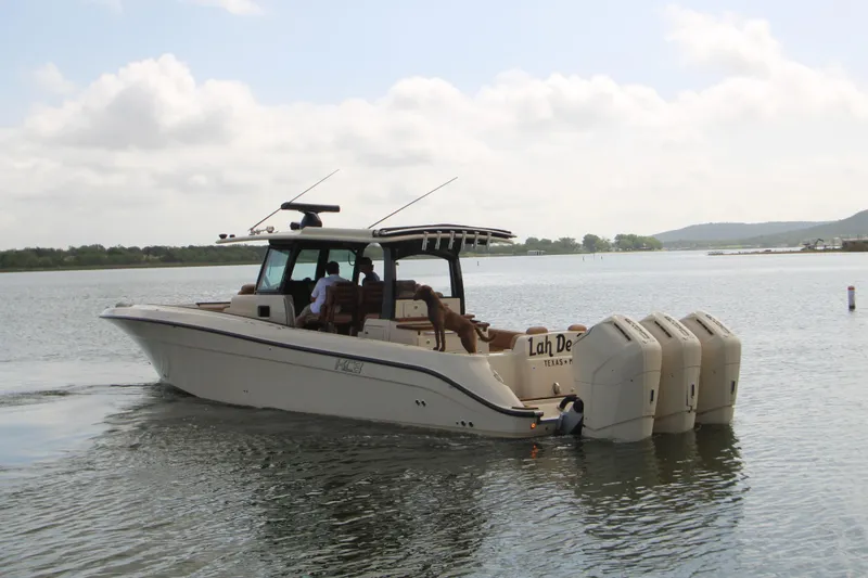 Slide: The Image of 2024 HCB 42 Lujo boat cruising on a calm lake with multiple outboard engines. - 104