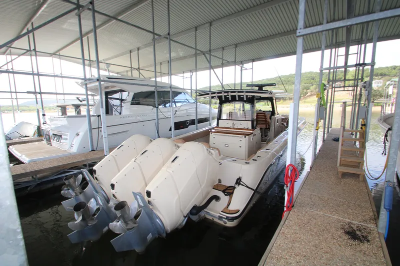 Slide: The Image of 2024 HCB 42 Lujo boat docked with powerful outboard engines in a covered marina. - 75