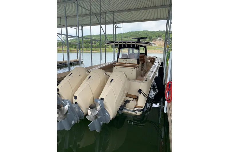 Slide: The Image of 2024 HCB 42 Lujo boat docked with triple outboard engines under a covered marina. - 83