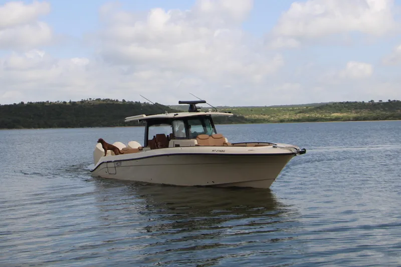 Slide: The Image of 2024 HCB 42 Lujo boat cruising on a serene lake under a partly cloudy sky. - 5