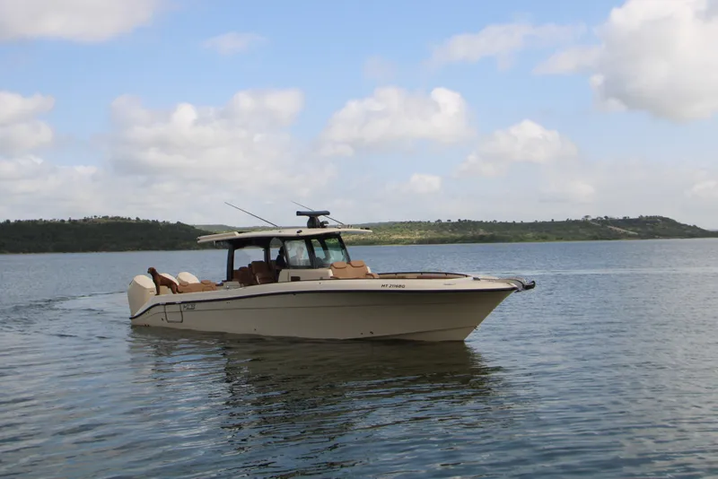 Slide: The Image of 2024 HCB 42 Lujo boat cruising on a serene lake under a partly cloudy sky. - 97