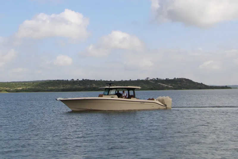 Slide: The Image of 2024 HCB 42 Lujo boat cruising on a serene lake under a partly cloudy sky. - 92