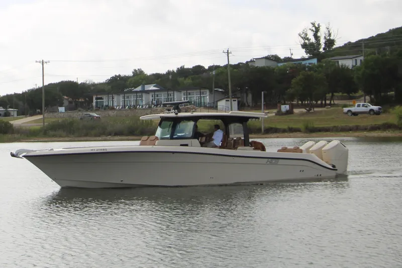 Slide: The Image of 2024 HCB 42 Lujo boat cruising on a calm lake near a residential area. - 109