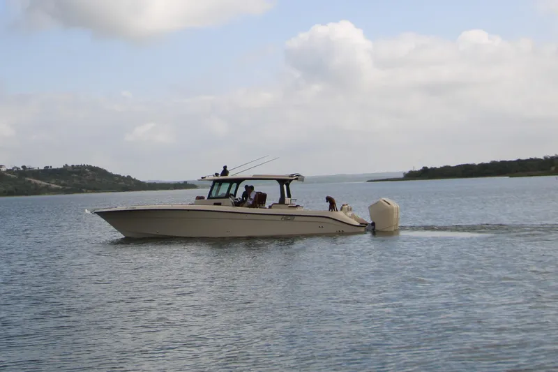Slide: The Image of 2024 HCB 42 Lujo boat cruising on a calm lake under a cloudy sky. - 93