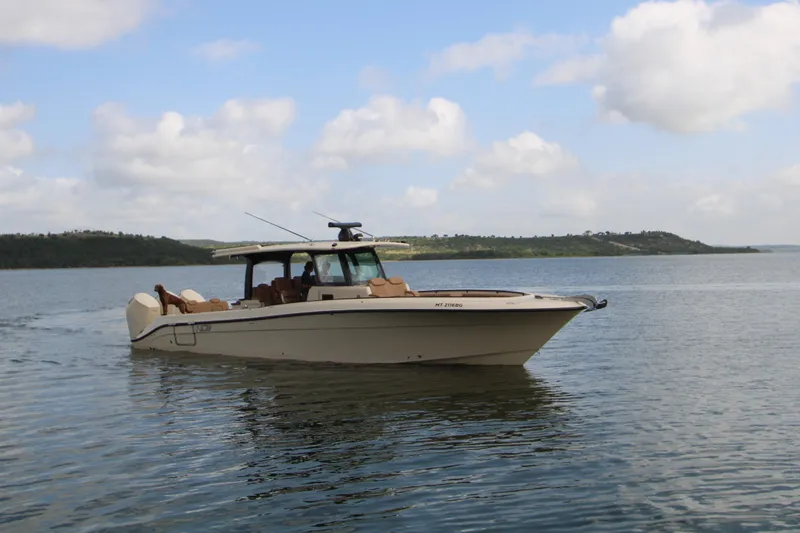 Slide: The Image of 2024 HCB 42 Lujo boat cruising on a calm lake under a partly cloudy sky. - 98