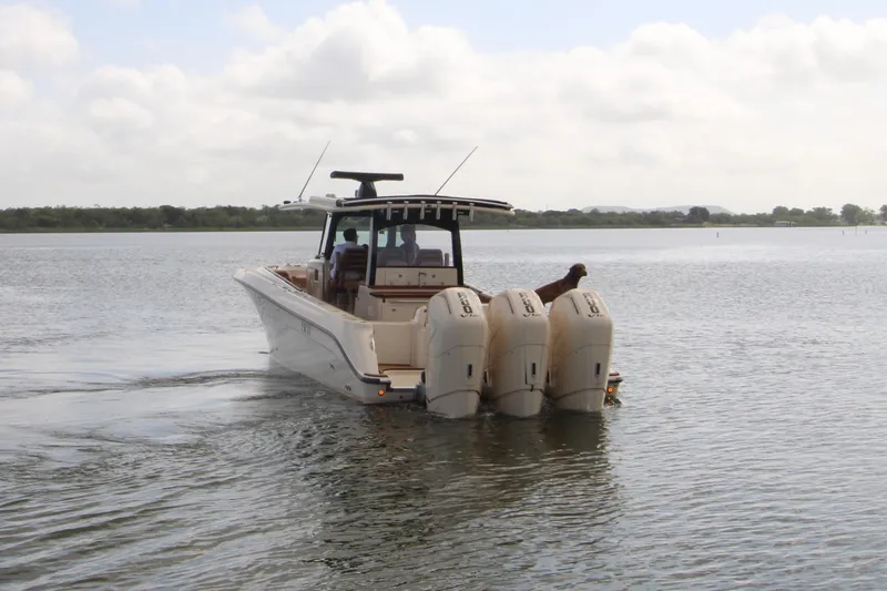 Slide: The Image of 2024 HCB 42 Lujo boat with triple outboard engines cruising on a calm lake. - 3