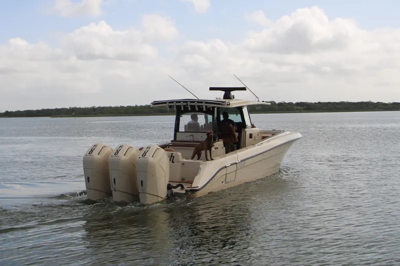 Slide: The Image of 2024 HCB 42 Lujo boat cruising on calm waters with triple outboard engines. - 4