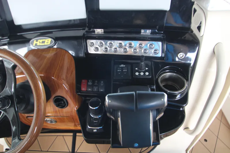 Slide: The Image of 2024 HCB 42 Lujo boat dashboard with controls, joystick, and wooden steering wheel. - 27