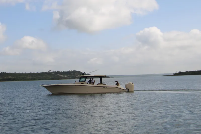Slide: The Image of 2024 HCB 42 Lujo boat cruising on a calm lake under a cloudy sky. - 91