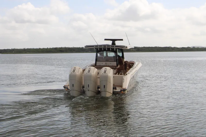 Slide: The Image of 2024 HCB 42 Lujo boat with triple engines cruising on a calm lake. - 101