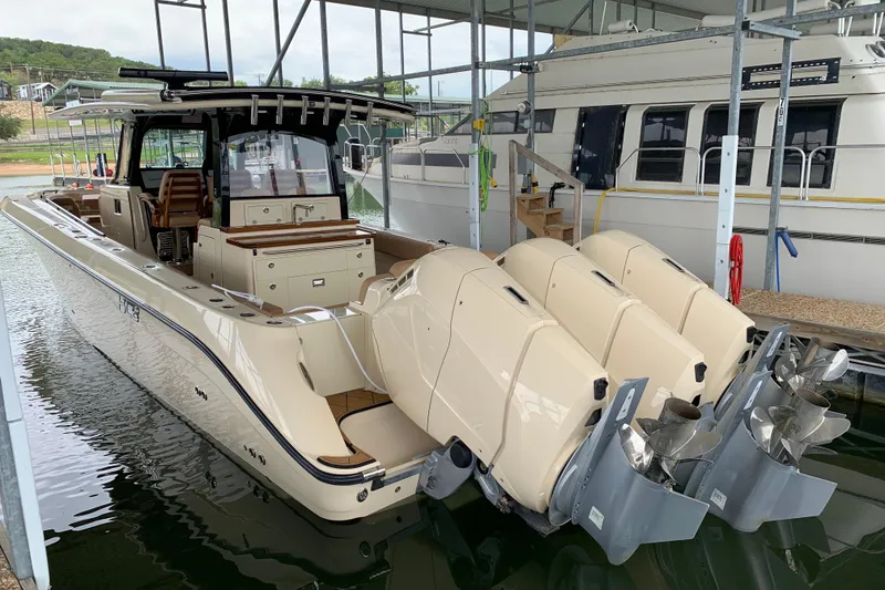 Slide: The Image of 2024 HCB 42 Lujo boat with triple outboard engines docked in a marina. - 74