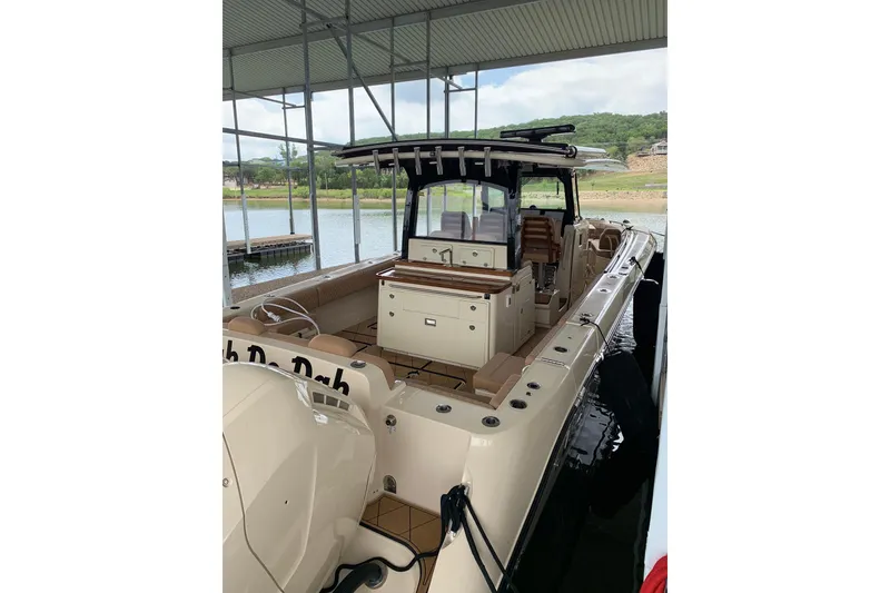 Slide: The Image of 2024 HCB 42 Lujo boat docked under a covered marina with scenic lake view. - 76