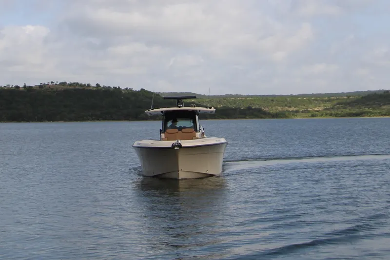 Slide: The Image of 2024 HCB 42 Lujo boat cruising on a serene lake under a cloudy sky. - 10