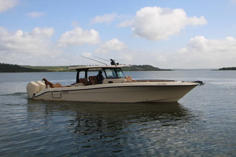 Slide: The Image of 2024 HCB 42 Lujo boat cruising on a calm lake under a partly cloudy sky. - 99