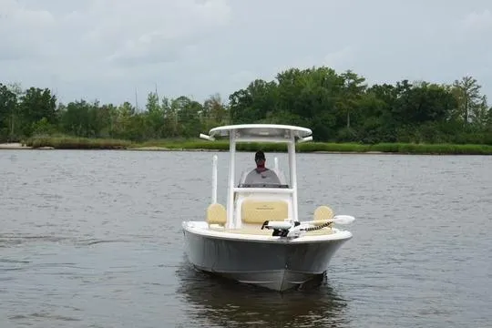 Slide: The Image of 2023 Sportsman Masters 227 Bay Boat cruising on a calm river with lush greenery. - 5