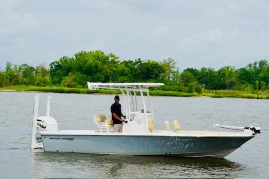 The Image of 2023 Sportsman Masters 227 Bay Boat on calm water, with lush green shoreline in background. - 1