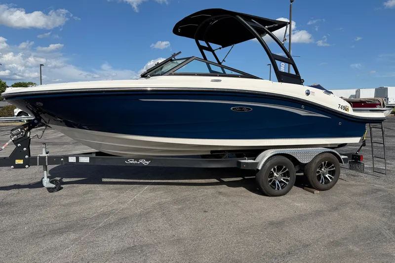 Slide: The Image of 2023 Sea Ray SPX 190 boat on trailer, blue and white design, parked outdoors. - 2