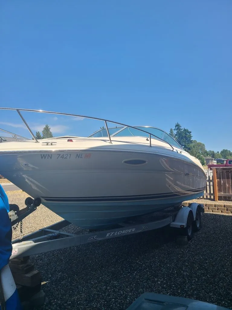 Slide: The Image of A 2002 Sea Ray 225 Weekender is on a trailer in a gravel lot. - 2