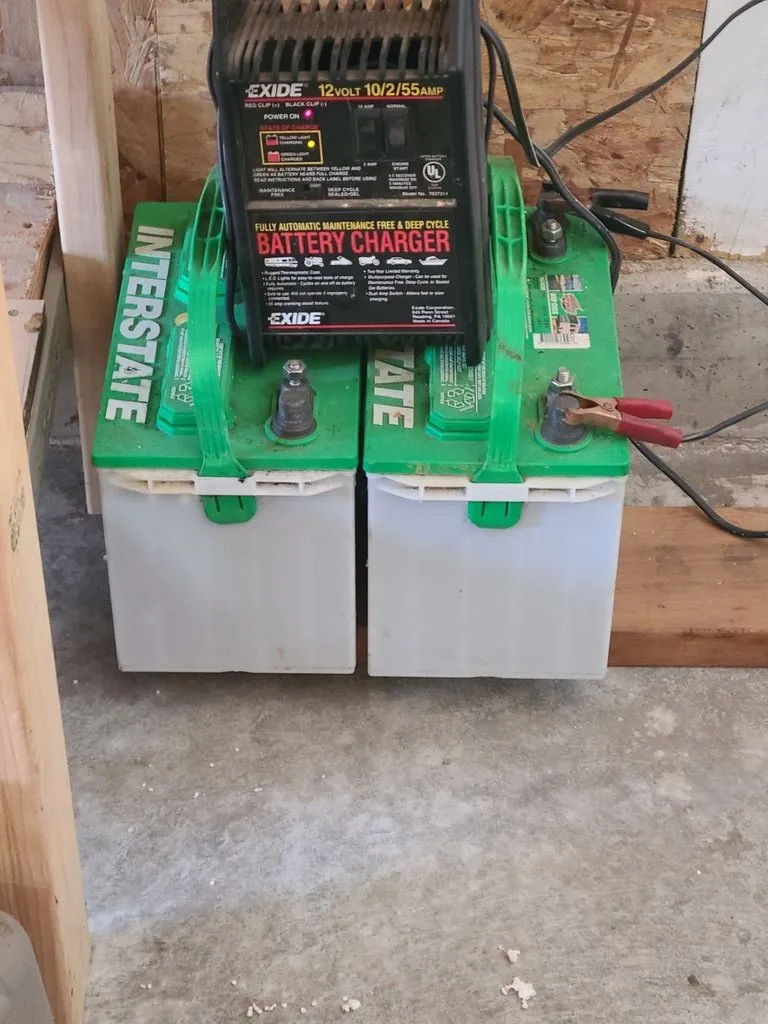 Slide: The Image of Two car batteries with a charger in a workshop setting. - 7