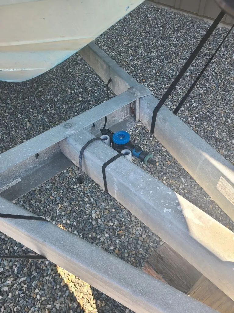 Slide: The Image of A boat trailer with a blue valve on a gravel surface. - 6