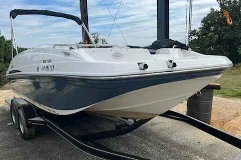 Slide: The Image of 2022 Hurricane SunDeck Sport 188 IO boat on trailer, white and blue design, parked outdoors. - 1