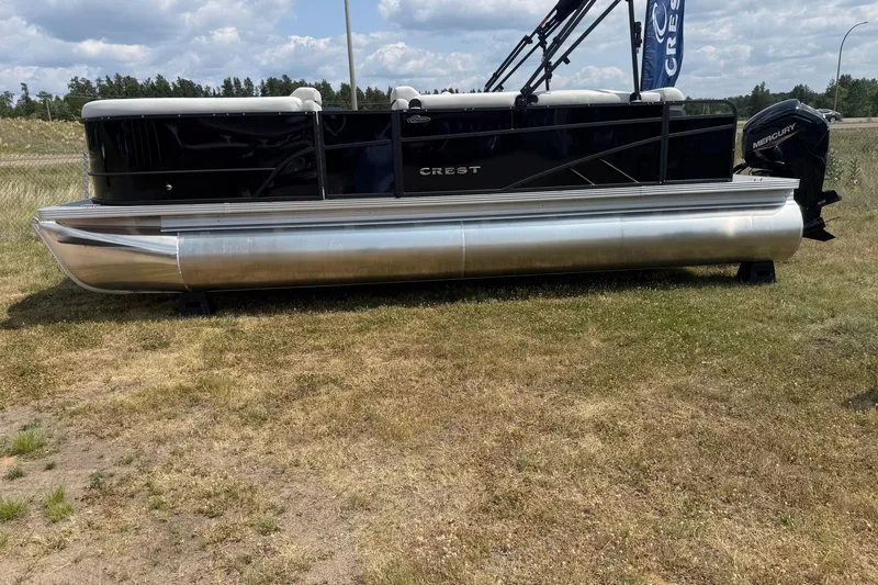 The Image of 2026 Crest Conquest SE220 Cruise pontoon boat on grassy terrain under cloudy sky. - 0