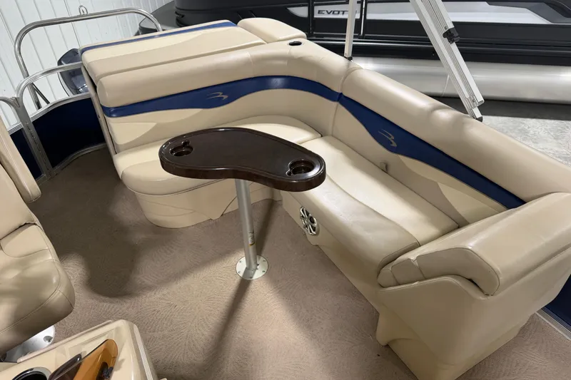 Slide: The Image of 2010 Bennington 20 SLI pontoon boat interior with beige seating and a wooden table. - 5