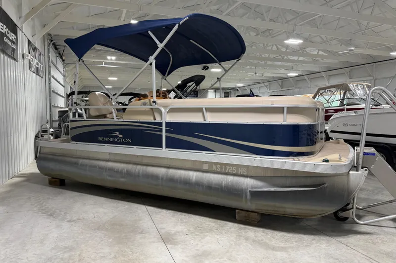 The Image of 2010 Bennington 20 SLI pontoon boat with blue canopy in indoor showroom. - 0