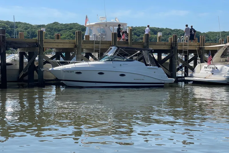The Image of 2020 Rinker 270 Express Cruiser docked at a marina with people on the pier. - 0