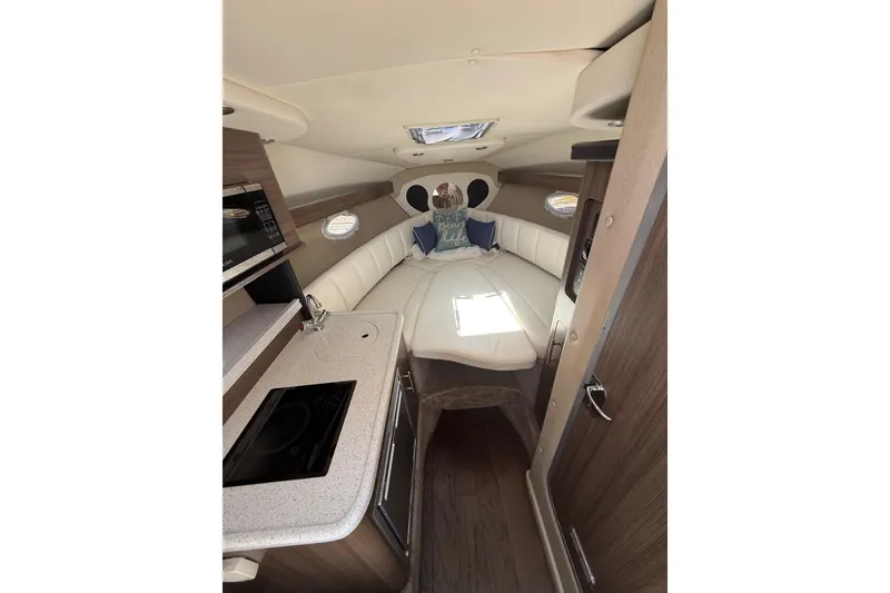 Slide: The Image of Interior of 2020 Rinker 270 Express Cruiser with kitchenette and cozy seating area. - 17