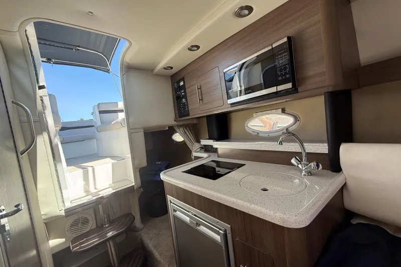 Slide: The Image of Interior of 2020 Rinker 270 Express Cruiser with kitchenette and seating area. - 14