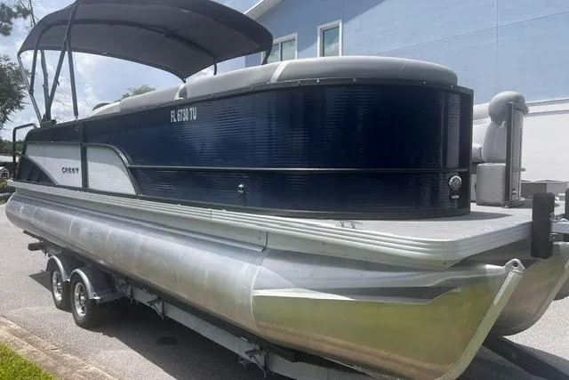 Slide: The Image of 2023 Crest Classic DLX 240 pontoon boat on trailer, parked outdoors. - 3