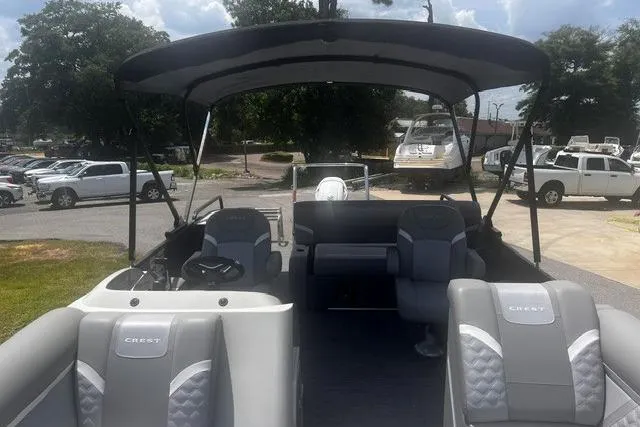 Slide: The Image of 2023 Crest Classic DLX 240 pontoon boat with spacious seating and canopy, parked outdoors. - 19