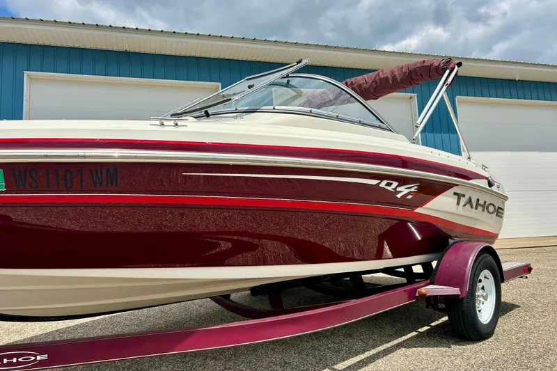 Slide: The Image of 2013 Tahoe Q4i boat with red and white design on trailer, parked near blue building. - 4