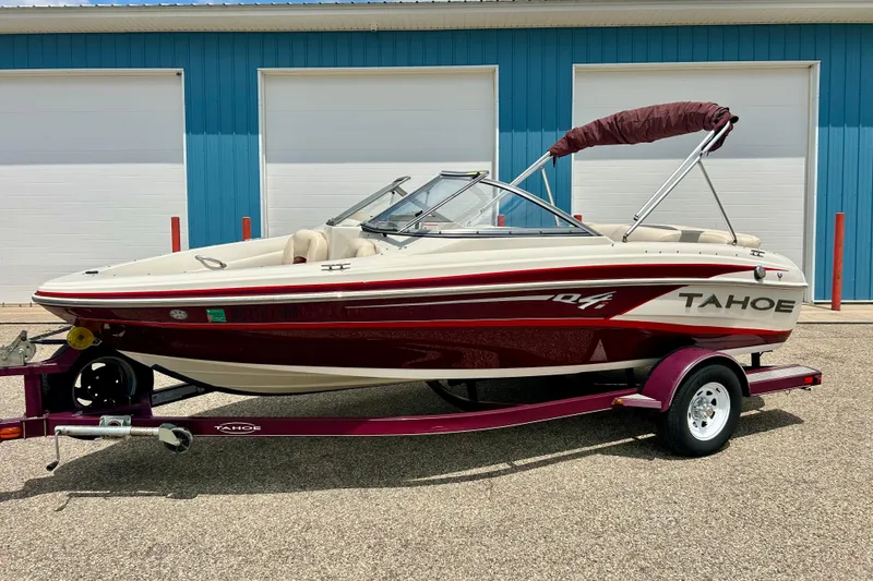 The Image of 2013 Tahoe Q4i boat on trailer, parked outside blue building. - 1