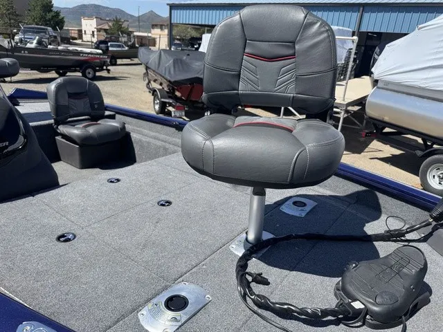 Slide: The Image of A 2021 Tracker Pro Team 175 TF with gray cushioned seats and fishing platforms outdoors. - 17
