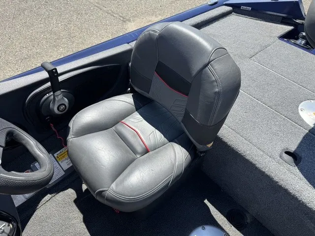 Slide: The Image of A gray padded seat in a boat with carpeted flooring and a steering console. - 27