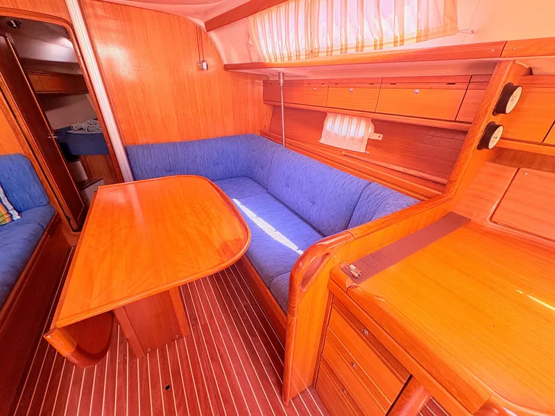 Slide: The Image of The interior of a 2008 Bavaria Cruiser 38 features a cozy seating area with blue cushions. - 24