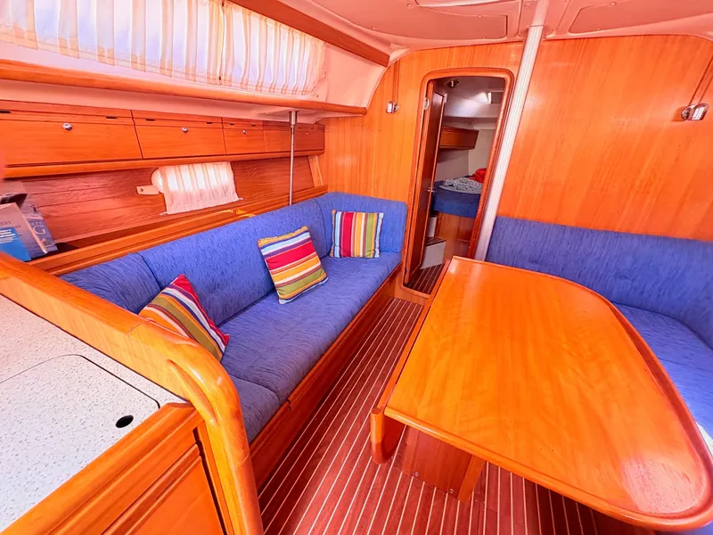 Slide: The Image of The interior of a 2008 Bavaria Cruiser 38 features a cozy seating area with blue upholstery and colorful cushions. - 25