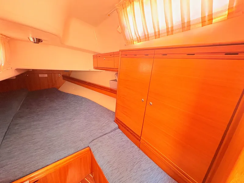 Slide: The Image of The cabin of a 2008 Bavaria Cruiser 38 with wooden cabinets and a blue bed. - 31