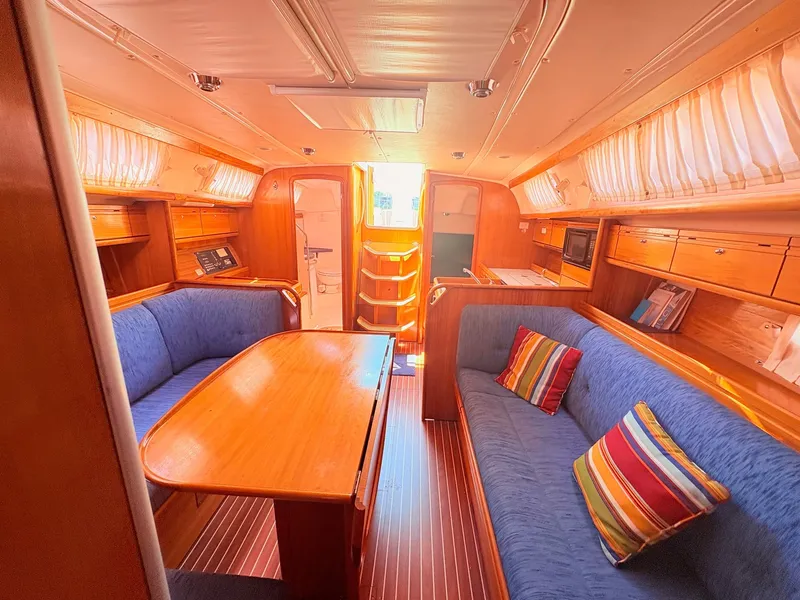 Slide: The Image of The interior of a 2008 Bavaria Cruiser 38 features a cozy seating area with a wooden table and blue upholstery. - 36