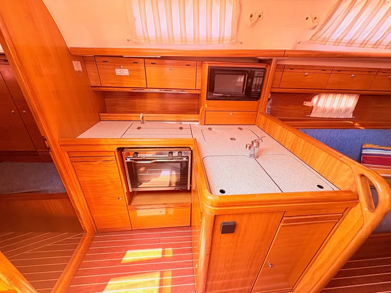 Slide: The Image of The interior of a 2008 Bavaria Cruiser 38 features a well-equipped kitchen with wood paneling, stove, and microwave. - 26