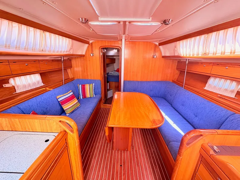 Slide: The Image of The interior of a 2008 Bavaria Cruiser 38 features a cozy seating area with blue cushions and a wooden table. - 19